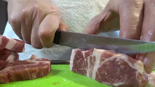 Una mujer corta un trozo grande de carne de cerdo con un cuchillo. Carne con capas de grasa, cuello de cerdo. — Vídeos de Stock