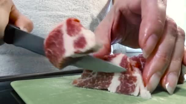 Женщина режет ножом большой кусок свинины. Мясо с жировыми слоями, свиная шея. — стоковое видео