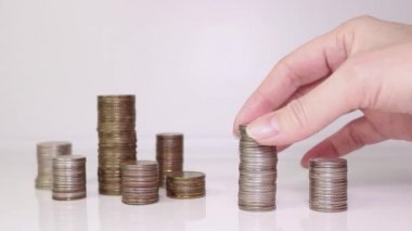 Bir kadının eli bir sütuna bozuk para koyar. Yatırım konsepti. Metalik para birimi.