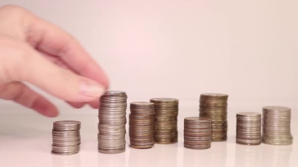 Die Hand einer Frau legt Münzen in eine Säule. Investitionskonzept. Metallische Währung. — Stockvideo
