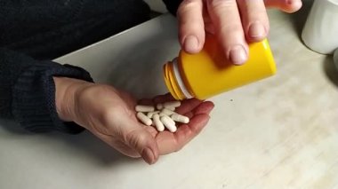Yaşlı bir kadın şişeden eline ilaç döküyor. Kırışıklıkları olan eller. Sağlığın korunması ve yaşlıların bakımının sağlanması. Yavaş çekim.