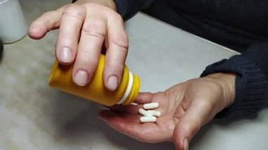 Yaşlı bir kadın şişeden eline ilaç döküyor. Kırışıklıkları olan eller. Sağlığın korunması ve yaşlıların bakımının sağlanması. Yavaş çekim.