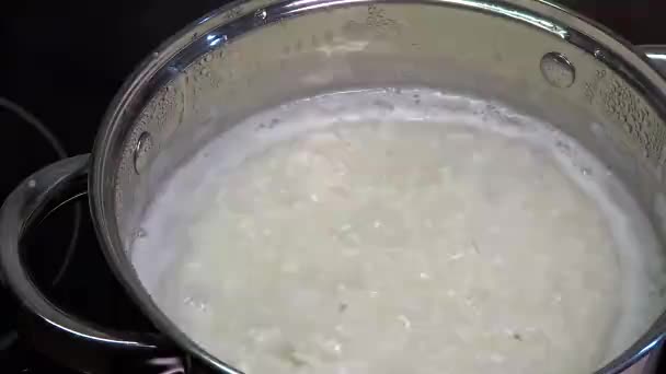 Reis wird in einem Topf gekocht. Brei zum Frühstück kochen. Beilage zu Hauptgerichten, Mittagessen. Siedendes Wasser und abgekochtes Getreide in Nahaufnahme. — Stockvideo