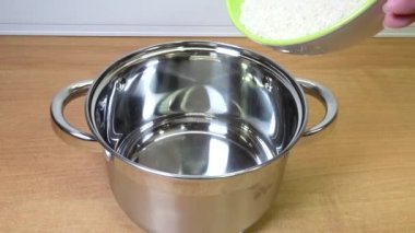 Pirinç ezmesi daha fazla pişirmek için yeni parlak bir tencereye dökülüyor..