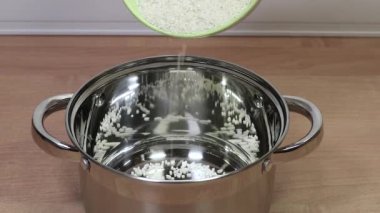 Pirinç ezmesi kaseden daha fazla pişirmek için parlak bir tencereye dökülüyor..