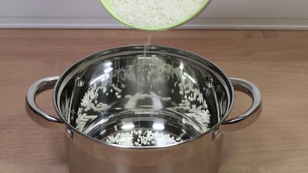 Rice grits falling from a bowl into a new shiny saucepan for further cooking. — Stock Video