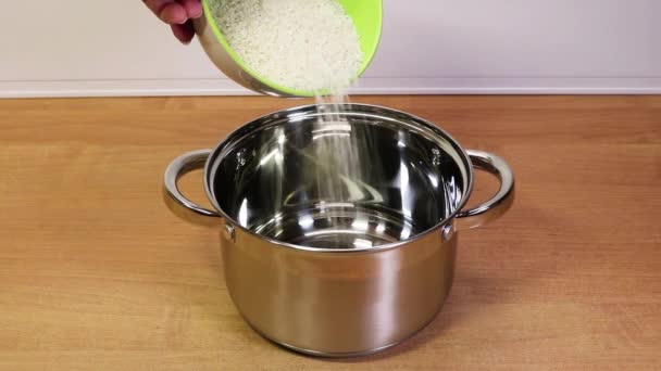 Rýžová krupice padající z misky do nového lesklého talíře pro další vaření. — Stock video