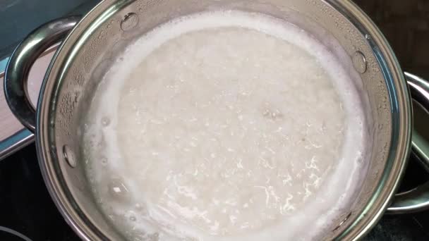 Le riz 4k est cuit dans une casserole. Cuisson du porridge pour le petit déjeuner. Accompagnement pour les plats principaux, déjeuner. Gros plan sur l'eau bouillante et les grains bouillis. — Video