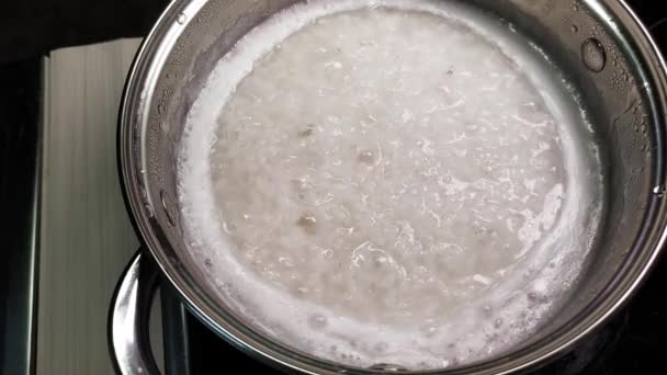 4k Reis wird in einem Topf gekocht. Brei zum Frühstück kochen. Beilage zu Hauptgerichten, Mittagessen. Siedendes Wasser und abgekochtes Getreide in Nahaufnahme. — Stockvideo