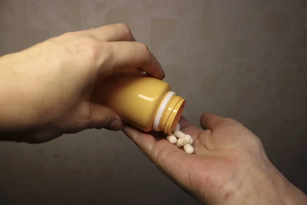 Women's hands pour pills from the jar. Medicinal capsules. Health care.