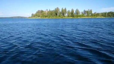 Göl yüzeyi dalgaları. Tekneyle suda hareket var. Blue Lake - Argazinskoe rezervuarı, Rusya.