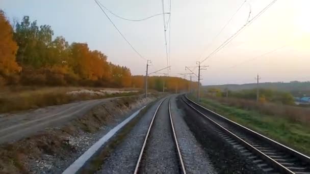 Vue de la fenêtre du dernier wagon du train au coucher du soleil, rails allant dans la distance. Été indien - feuilles jaunes d'arbres. Concept voyage en train. — Video