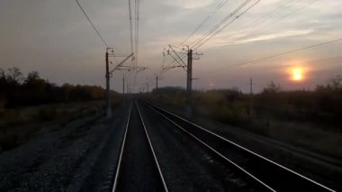 Gün batımında, tren şoförünün taksisinin manzarası, raylar mesafeye gidiyor. Hint yazı- ağaçların sarı yaprakları. Tren yolculuğu konsepti.