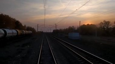Gün batımında trenin son vagonunun penceresinden bak, raylar uzaklaşıyor. Tankları olan bir yük treni. Tren yolculuğu kavramı.