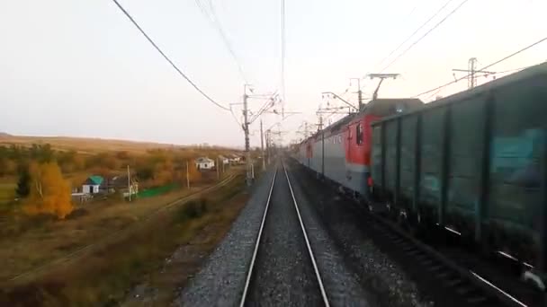 Vue de la fenêtre du dernier wagon du train au coucher du soleil, rails allant dans la distance. Le train de marchandises roule sur des rails venant en sens inverse. Concept voyage en train. — Video