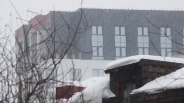 İnşaat halindeki bir binanın arka planında kar yağışı var. Kış şehri, Ocak.