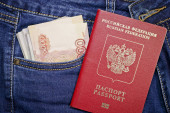 Hromada ruských pětitisícin a tisíc rublů v kapse modrých džínů a ruském mezinárodním pase. Peníze v hotovosti. Cestovní koncept.