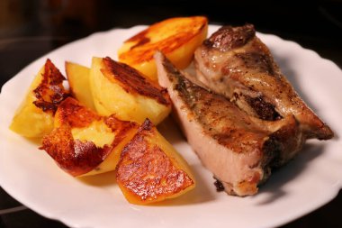 Beyaz tabakta patatesli fırında et. Yemekte çıtır çıtır ekmek..