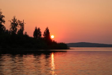 Gölün sakin su yüzeyinde renkli bir gün doğumu. Yaz manzarası. Argazinskoe rezervuarı, Chelyabinsk, Rusya