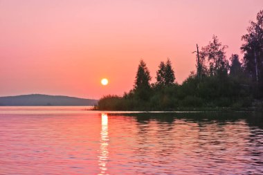Gölün sakin su yüzeyinde renkli bir gün doğumu. Yaz manzarası. Argazinskoe rezervuarı, Chelyabinsk, Rusya