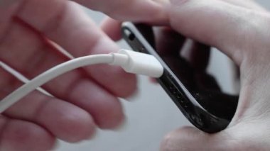 C tipi USB kabloyu şarj etmek için akıllı telefon bağlantısına takan bir kadın. Telefon için özel şarj bağlantısı.