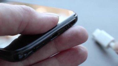 C tipi USB kabloyu şarj etmek için akıllı telefon bağlantısına takan bir kadın. Telefon için özel şarj bağlantısı.