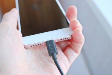 Kadın USB kablosunu şarj etmek için akıllı telefon bağlantısına takıyor. Telefon için özel şarj bağlantısı.