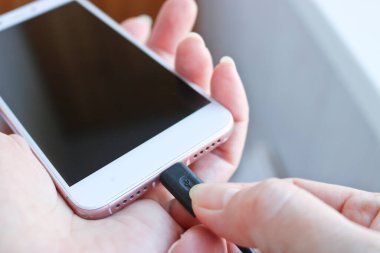 Kadın USB kablosunu şarj etmek için akıllı telefon bağlantısına takıyor. Telefon için özel şarj bağlantısı.