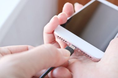 Kadın USB kablosunu şarj etmek için akıllı telefon bağlantısına takıyor. Telefon için özel şarj bağlantısı.