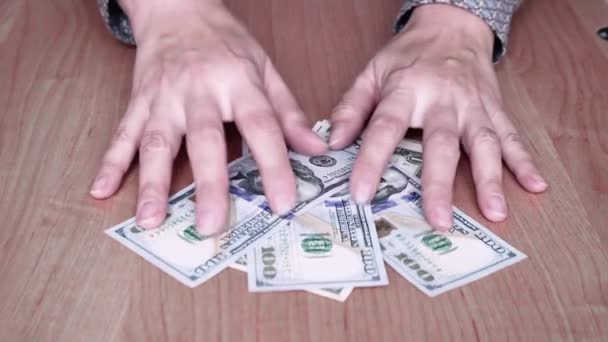 Women's hands move a pack of American bills across the table towards them. — Vídeo de Stock