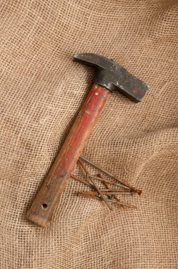 Kaba kumaş arka plan üzerinde çekiç, paslı çivi.