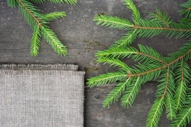 Tahta bir masanın üzerinde fidan dalı ve kaba bir çuval bezi.