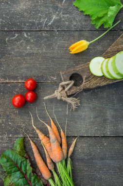 Eski ahşap kesme tahtasının üzerinde taze sebzeler. Kırsal biçim