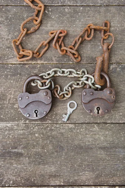 Due vecchio lucchetto arrugginito e catena arrugginita su sfondo di legno. Il concetto di una relazione di coppia — Foto Stock