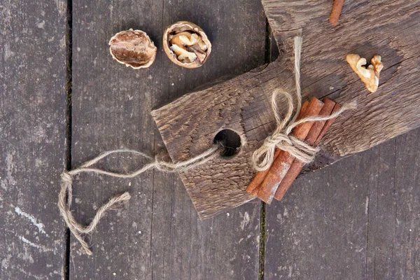 Paus de canela e noz em uma tábua de madeira, foto estilo rústico — Fotografia de Stock