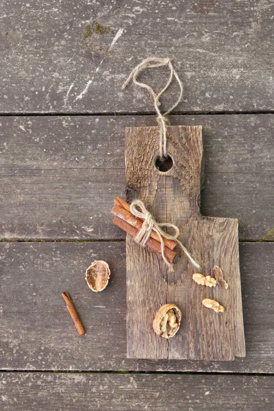 Palitos de canela y nogal en una tabla de madera, estilo rústico foto — Foto de Stock