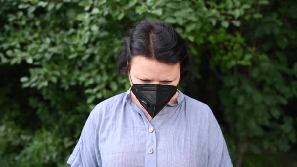 Žena v lékařské masce zvedne hlavu a vzhlédne. Černý respirátor. Pandemic koncept video záběry 4k — Stock video