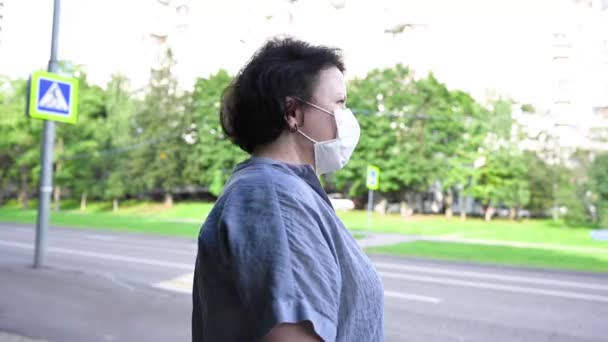 Žena v lékařské masce na ulici ve městě. Video se statickou kamerou. — Stock video