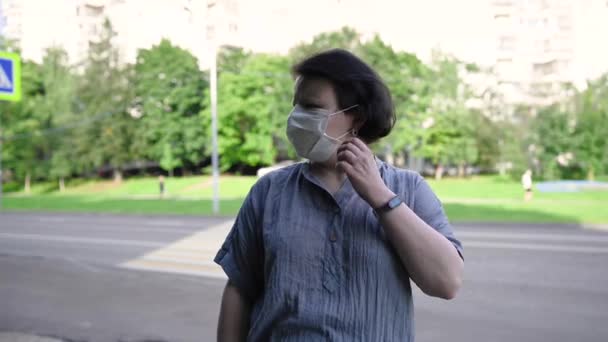 En kvinna i medicinsk mask på gatan i stan. Video med en statisk kamera. — Stockvideo