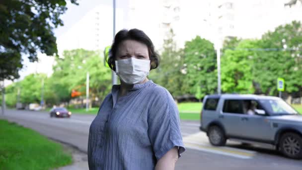 Žena v lékařské masce na ulici ve městě. Video se statickou kamerou. — Stock video