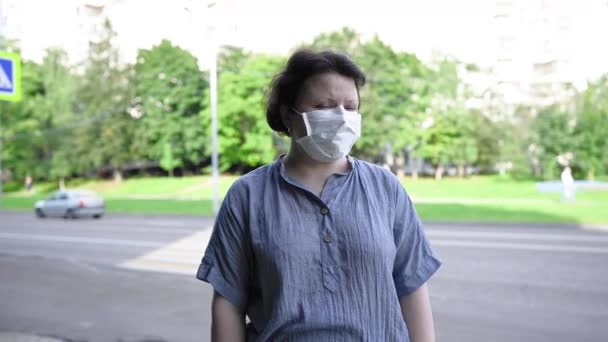 Una mujer con una máscara médica en la calle de la ciudad. Video con una cámara estática. — Vídeo de stock