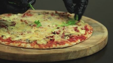 Tahta bir tabakta pişmiş pizza roka üzerine serilmiş.