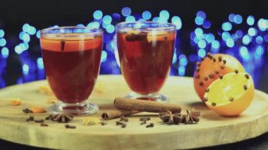 Koyu bir arka planda, ahşap bir tabakta dönen iki bardak sıcak şarap.
