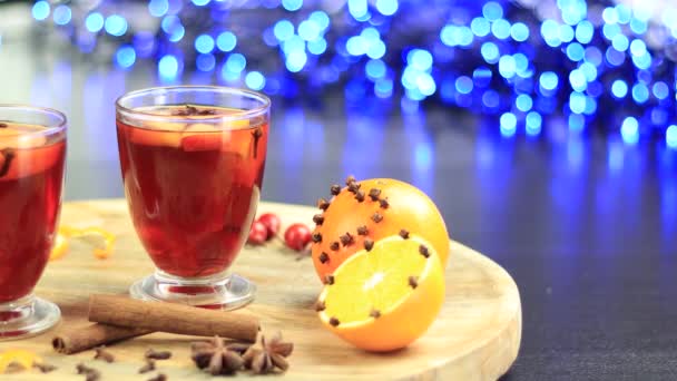 Two glasses of mulled wine rotating on a tray with orange and cynamon — Stock Video