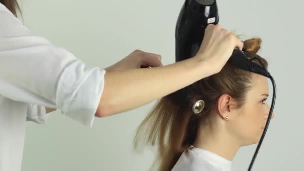 Stylista suszy włosy suszarką do włosów i okrągłym grzebieniem — Wideo stockowe