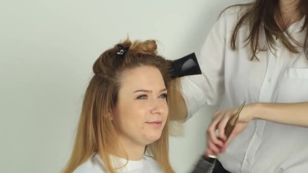 Kuaför, genç bir kıza saç kurutma makinesiyle saç kurutur. — Stok video