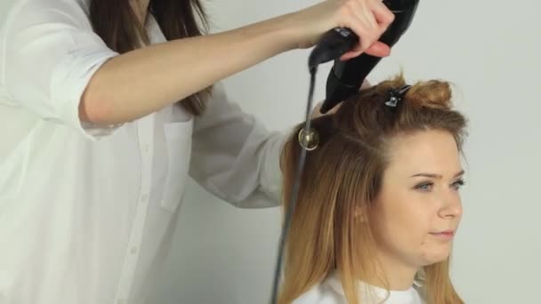 Stylist asciuga i capelli con un pettine rotondo e asciugacapelli — Video Stock