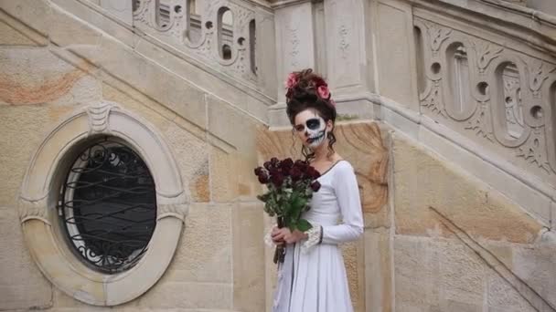 Menina na imagem de um demônio com maquiagem para o Halloween, com rosas nas mãos. — Vídeo de Stock