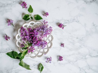  Mermer bir masanın üzerindeki bir tabakta leylak.