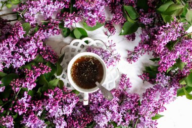 Misket masasındaki leylak arkaplanında bir fincan bitki çayı. Bahar. Romantik ruh hali